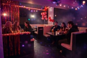 Skupina přátel v rezervovaném boxu ve friendly karaoke baru v Praze